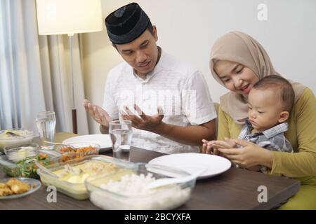 muslim family pray before having dinner together on ramadan Stock Photo