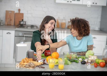 Two young girlfriends chatting in the kitchen. Stock Photo