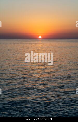 The sun is setting over the ocean Stock Photo