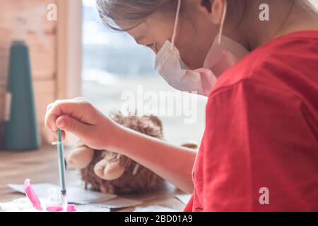 Child girl plays doctor at home and treats a teddy bear Stock Photo