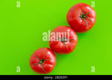Three large red juicy fresh tomatoes lie on a green table. Close-up. White background. Copy space Stock Photo