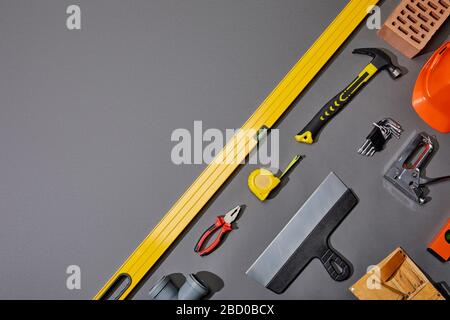 flat lay with brick, hammer, measuring tape, helmet, tool belt and industrial tools on grey background Stock Photo