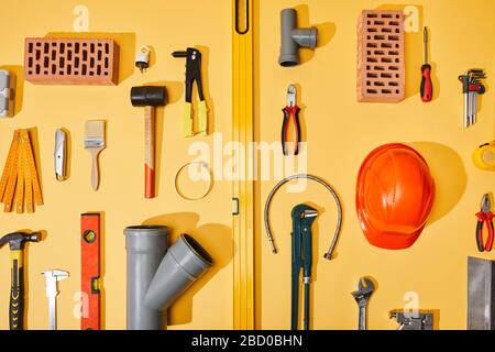 flat lay with industrial tools, bricks and helmet on yellow background Stock Photo
