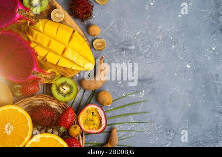 A set of papaya, dragon fruit, rambutan, tamarind, mango, passion fruit, kiwi, orange, strawberry, green leaves on gray stone background with copy spa Stock Photo