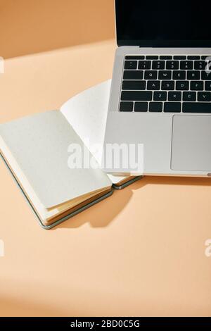 high angle view of opened blank notebook and laptop on beige background Stock Photo