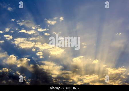 Evening sun rays streaming through clouds Stock Photo