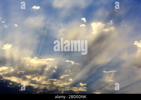 Evening sun rays streaming through clouds Stock Photo