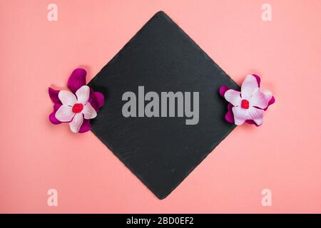 Black square with purple and white flowers on a pastel pink background Stock Photo