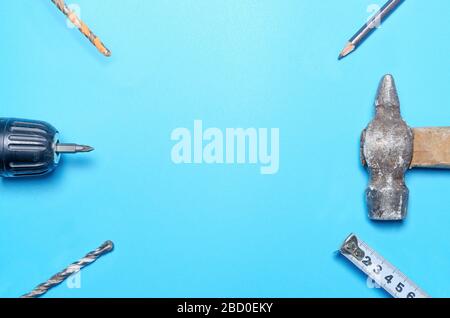 construction and repair tools, tape measure, hammer, marking pencil, drills, screwdriver. on a blue background. Flat lay. Stock Photo