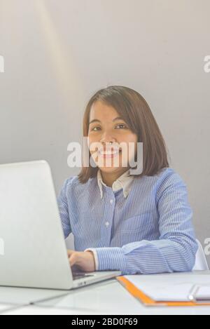 Portrait of woman smiling and using laptop at business office Stock Photo