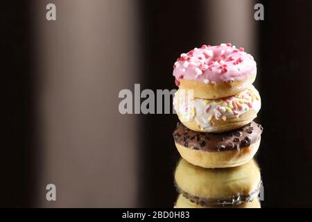 Three different donuts with reflection on a light and dark background. Stock Photo