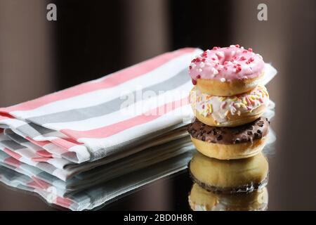 Three different donuts and kitchen towel with reflection on a light and dark background. Stock Photo