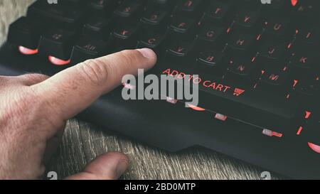 Man pressing add to cart button on laptop keyboard home computer online shopping home delivery concept Stock Photo
