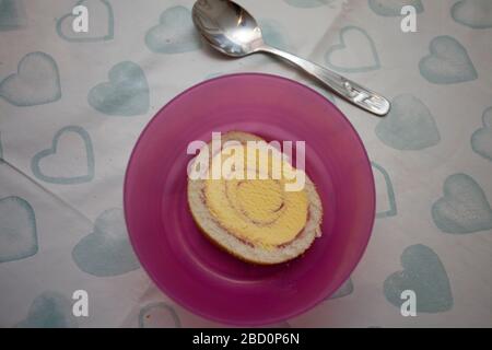 Arctic roll slice in a pink bowl with spoon Stock Photo
