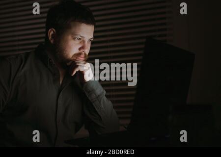 Thoughtful man reading article by laptop at nigth. Stock Photo