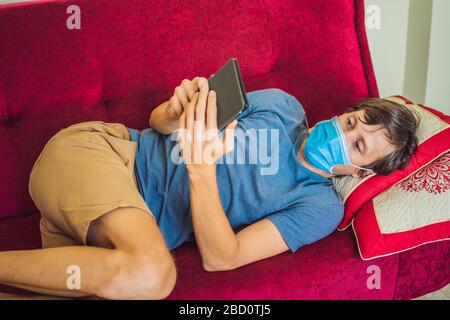 E-book and online education. A man is reading a quarantined book at home. A man in a medical mask remained at home in self-isolation Stock Photo
