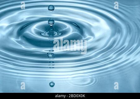 Water drops splash in a glass blue colored Stock Photo