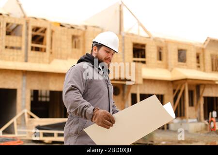 Foreman holding architecture drawing plan on paper at construction site. Stock Photo