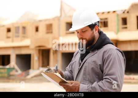Caucasian engineer drawing plan in notebook at construction site. Stock Photo