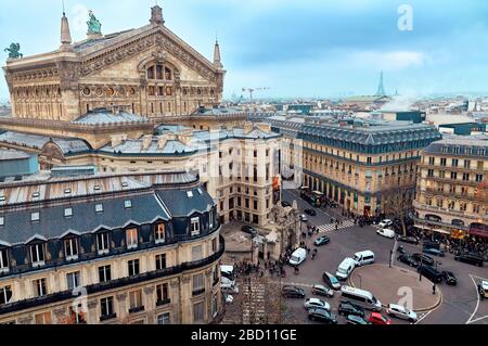 Opera Garnier (Garnier Palace) in cloudy, dramatic cityscape. Aerial view from the roof of Galeries Lafayette Haussmann. Eiffel Tower in background