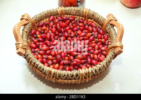 red rose hips in basket . Fresh harvested rose hips in the basket. A basket of red rose hips . Freshly picked rose hips in a basket . Stock Photo