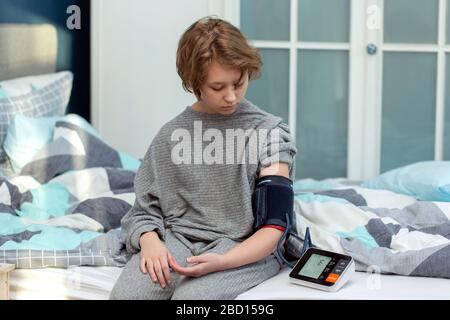 young girl looking at tonometer while measuring blood pressure , checking teenage girl's blood pressure in home Stock Photo
