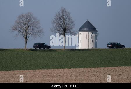 06 April 2020, Saxony-Anhalt, Crölpa: Cars drive on a country road in the Burgenlandkreis, while the top of a water tower towers over a hill. During the next few days, mild spring weather prevails in Central Germany. Photo: Sebastian Willnow/dpa-Zentralbild/dpa Stock Photo