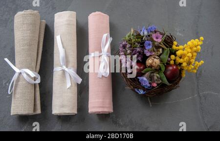 Easter composition with a nest of quail eggs and linen napkins, rolled and tied with ribbons.  Stock Photo