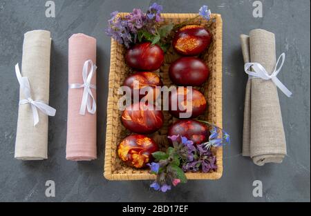 wicker basket full of colored Easter eggs , linen napkins on a gray background. Stock Photo