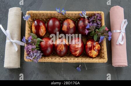 wicker basket full of colored Easter eggs , linen napkins on a gray background. Stock Photo
