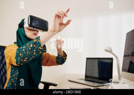 Muslim software developer testing new application she created for virtual reality headset Stock Photo