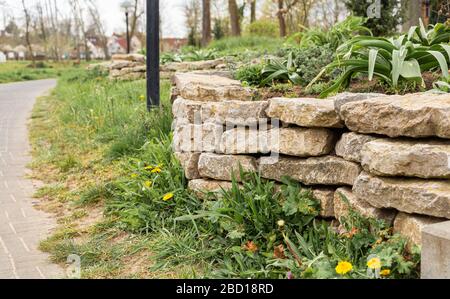 Wall made of stones in a city park. City Gardens. Fenced off from the lawn. Retaining wall. Stock Photo