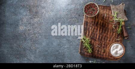 Top view of rectangular chopping board with preps and seasonings covering the right third of a dark blue metalic background. Stock Photo