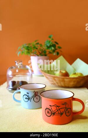 Vertical Image of Two cups of coffee with blurry fruits and planter in the backdrop Stock Photo