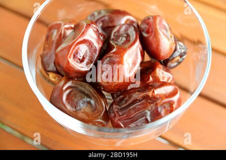 Closeup Dried Dates in a Glass Compote on Wooden Table Stock Photo