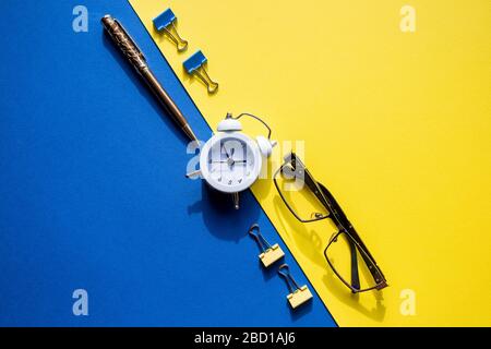 golden pen, stylish glasses, clips for paper and alarm clock lying on colorful background Stock Photo
