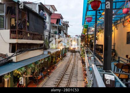 A train travels through Train St Hanoi, Vietnam. Stock Photo
