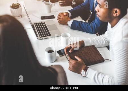 A team of young office workers, businessmen with laptop working at the table, communicating together in an office. Corporate businessteam and manager Stock Photo