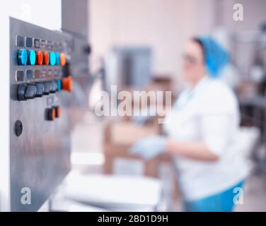 Control panel of an automatic line in production. Woman worker packs products at the factory. Industry, copy space, production line Stock Photo
