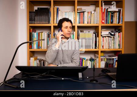 Photographer, wearing a white shirt and glasses, editing photos on a graphics tablet at home. Stock Photo