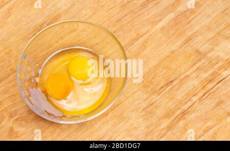 Two chicken eggs, homemade and factory, are broken in a glass plate. Difference concept of homemade natural eggs from store-bought, organic Stock Photo