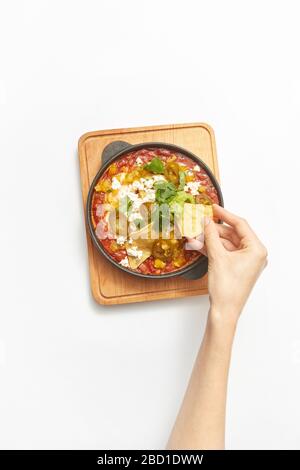 Woman's hand takes Shakshouka healthy food from the pan. Stock Photo