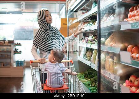 muslim asian Mother hijab and baby shopping in the supermarket. grocery store shopping Stock Photo