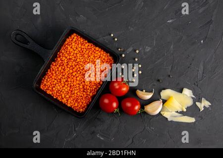 Still life food set on dark background. Concept shealthy eating. Lentils in frying pan, cheese, garlic and cherry tomato. Top views, close-up Stock Photo