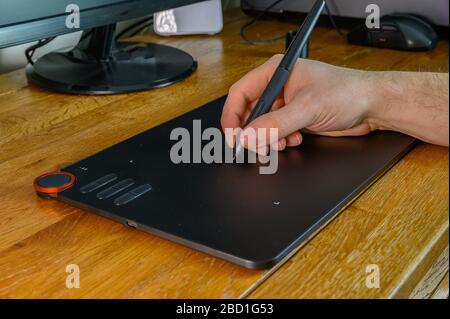 Isolated male hand on oak desk operating pen tablet (design concept) Stock Photo