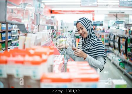 muslim asian woman shopping in grocery store supermarket buying some product Stock Photo