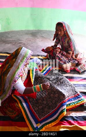 Women embroidering traditional tribal quilts in their bhunga (circular village mud house), Bhirindiara, Kutch, Gujarat, India, Asia Stock Photo