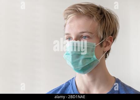 COVID-19 coronavirus. Portrait of an young man, 17 years old, in a medical mask.