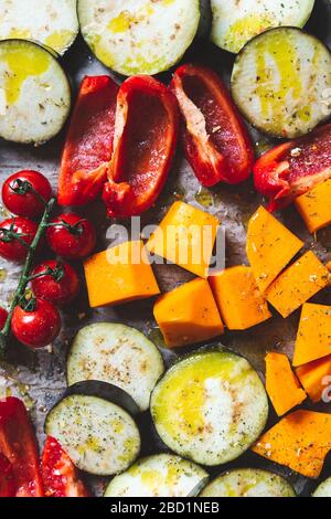 Healthy Detox Dinner from different vegetables such as aubergine, red pepper, cherry tomatoes, butternut squash. Slices of Raw vegetables prepared for the roasting, simple family meal Stock Photo