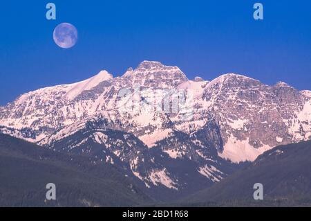 moon over peaks of the mission range above elk creek valley near condon, montana Stock Photo